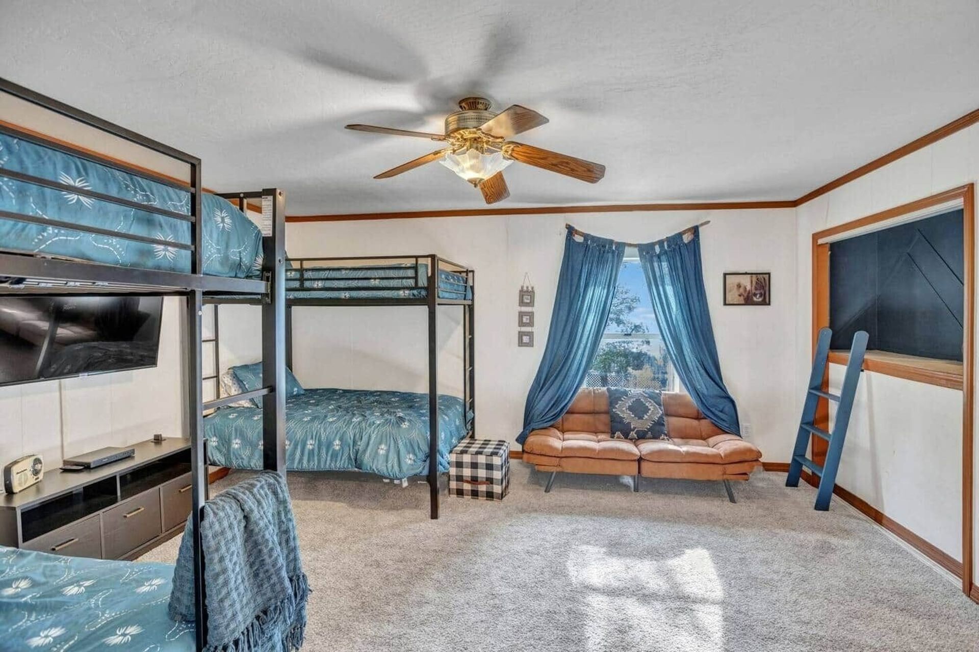 Shared bedroom with bunk beds, blue curtains, a ceiling fan, and a large window.