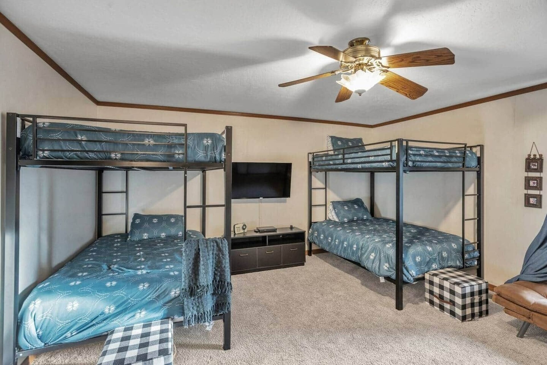 Bedroom with two bunk beds, blue bedding, a ceiling fan, TV, and beige carpet.