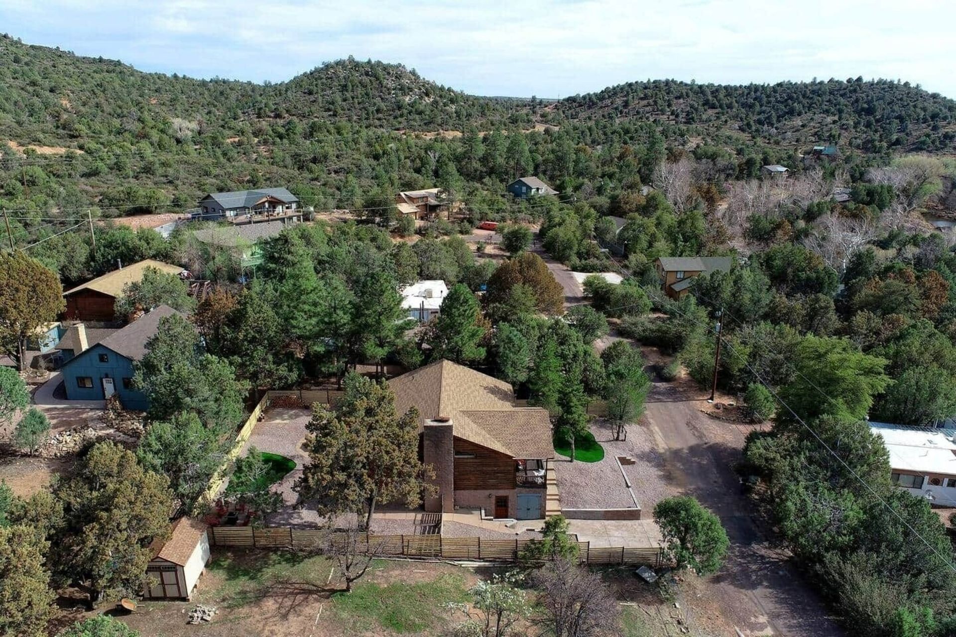 Aerial view of houses and trees in a hilly rural neighborhood under clear daylight