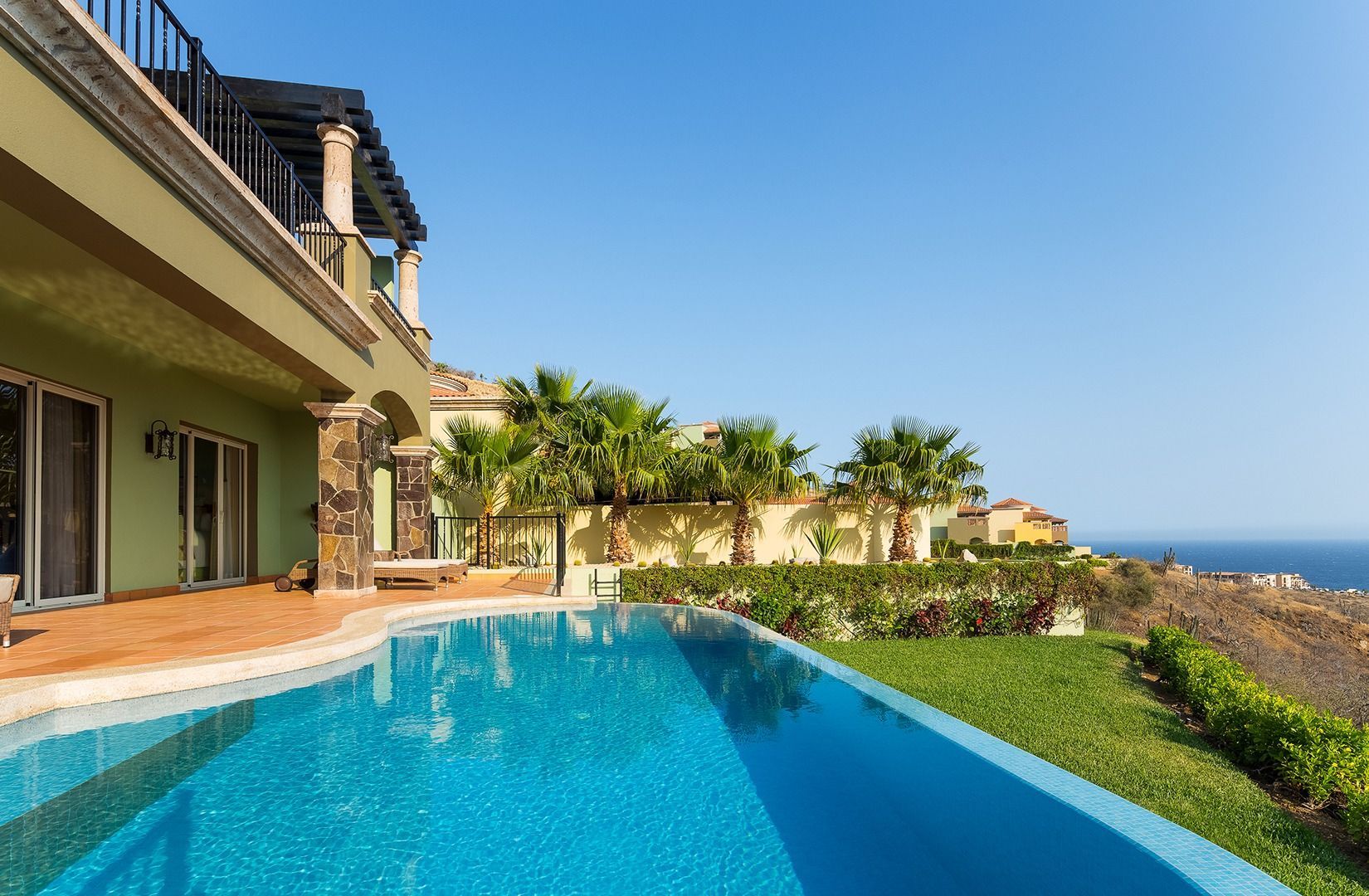 Luxurious seaside villa with an infinity pool overlooking the ocean under a clear blue sky