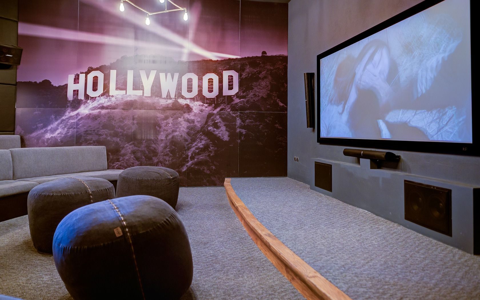 Home theater room with a Hollywood mural, gray seating, and a large wall-mounted screen