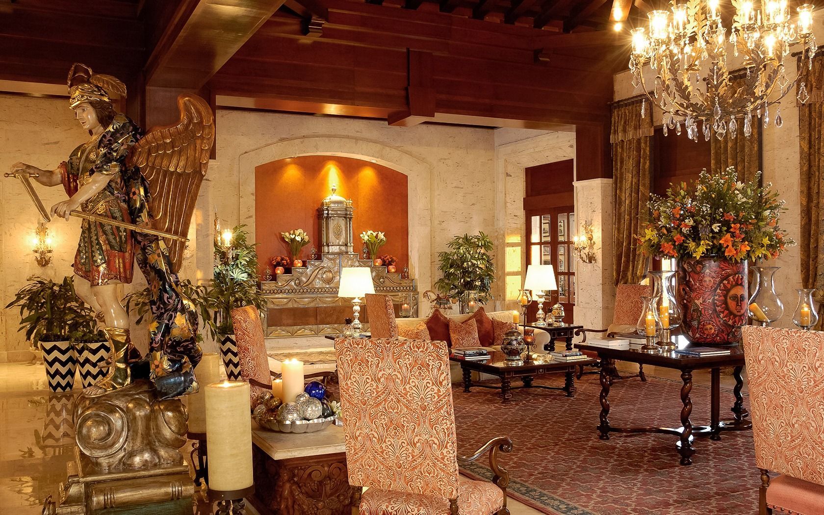 Elegant living room with chandelier, ornate decor, and arched fireplace glowing in warm light