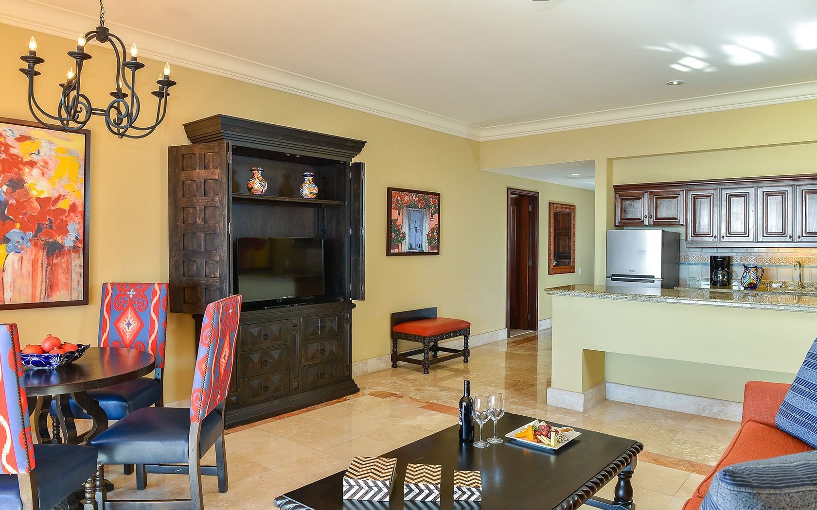Living room with dark fireplace, colorful chairs, and open kitchen in the background