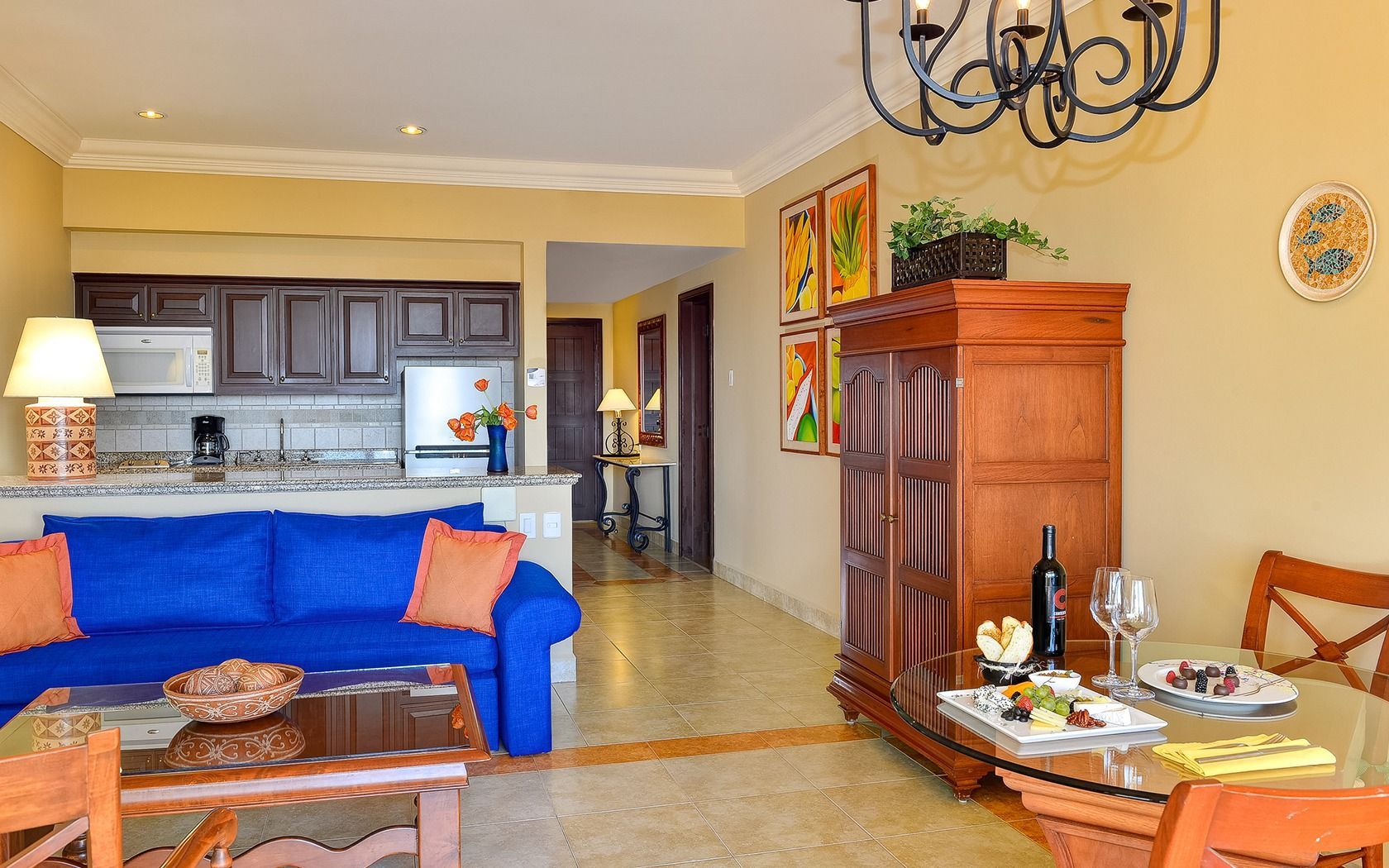 Bright living room with blue sofa, wooden cabinet, dining table, and open kitchen.