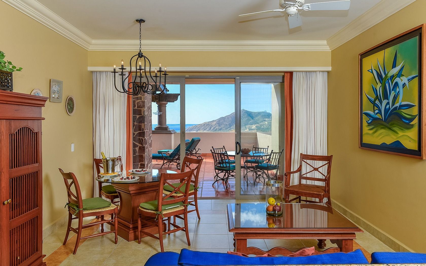 Bright dining room with wooden table, yellow walls, and sliding doors opening to a mountain-view patio.