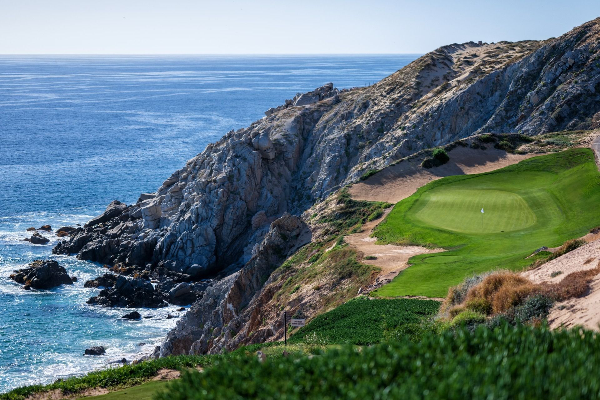 Rocky seaside golf course beside blue ocean and cliffs