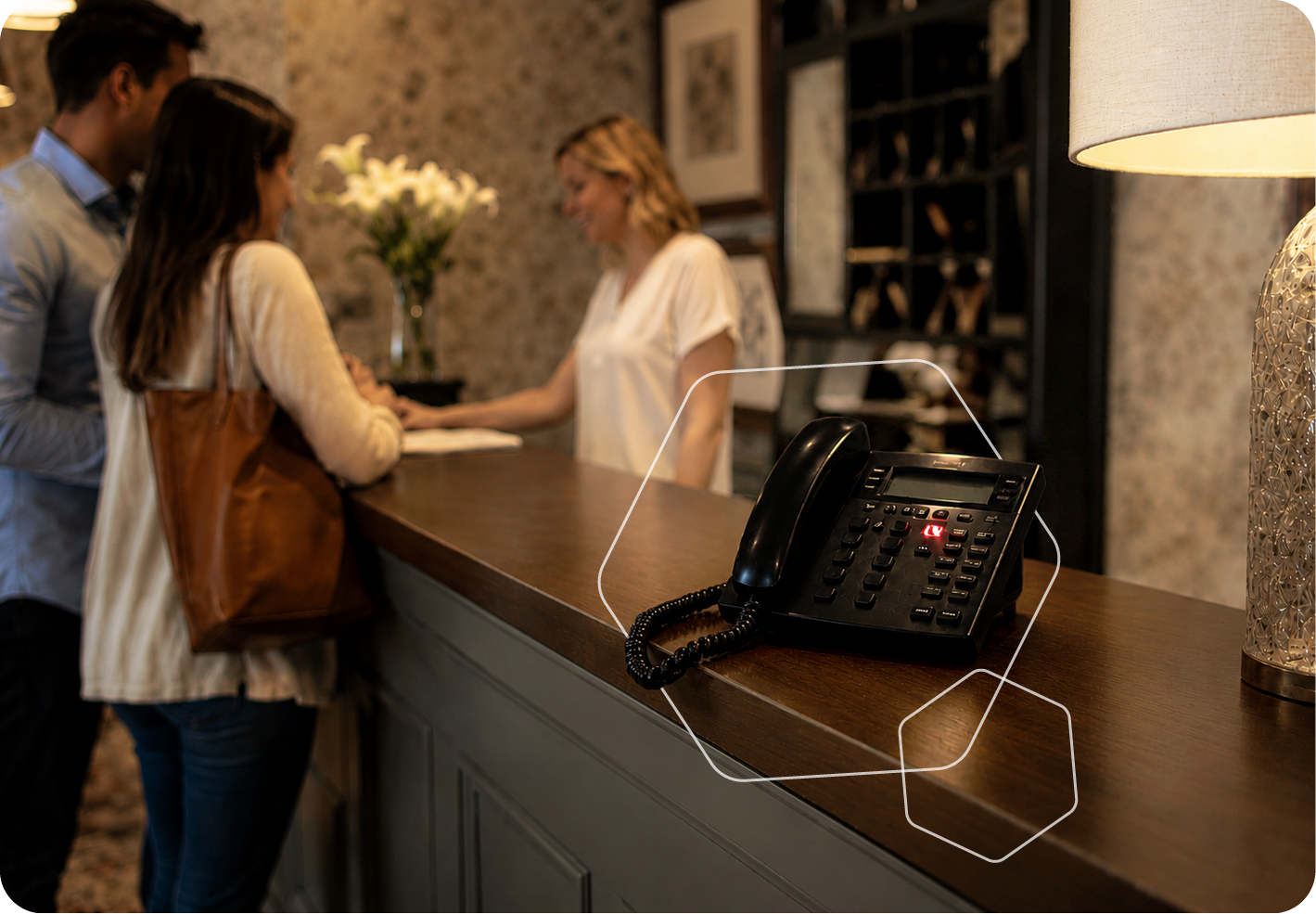 Hotel reception desk with guests checking in and a black office phone on the counter