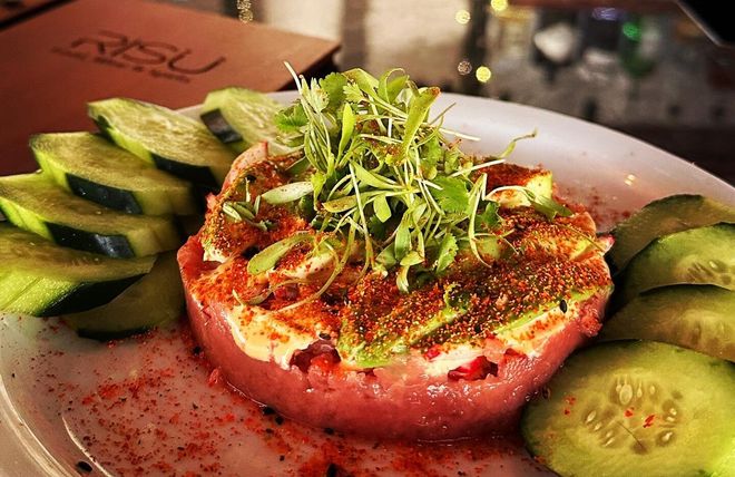 Colorful plated appetizer with avocado slices, tomato round, greens, and cucumber garnish