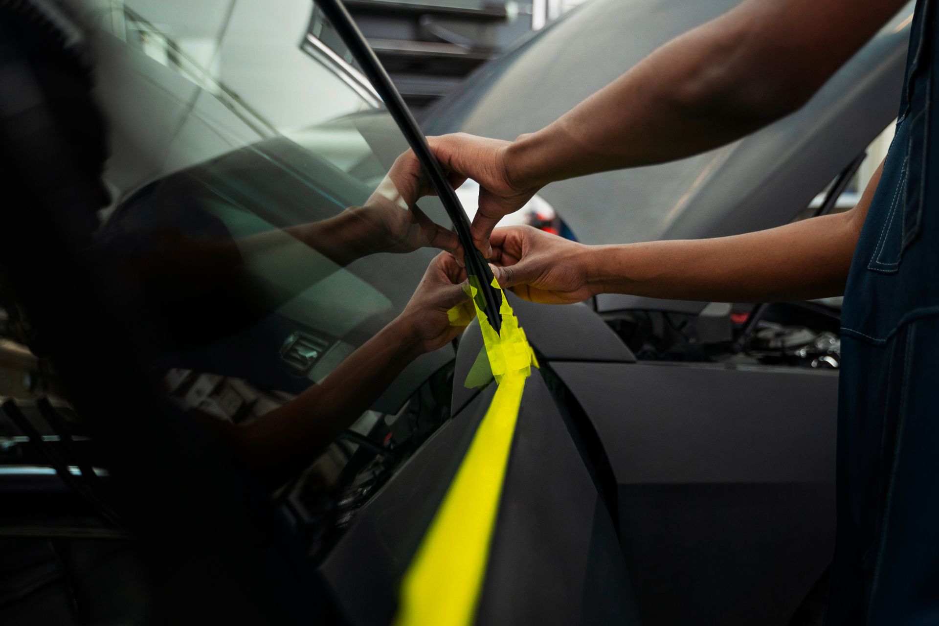 A person is wrapping a car with yellow tape.