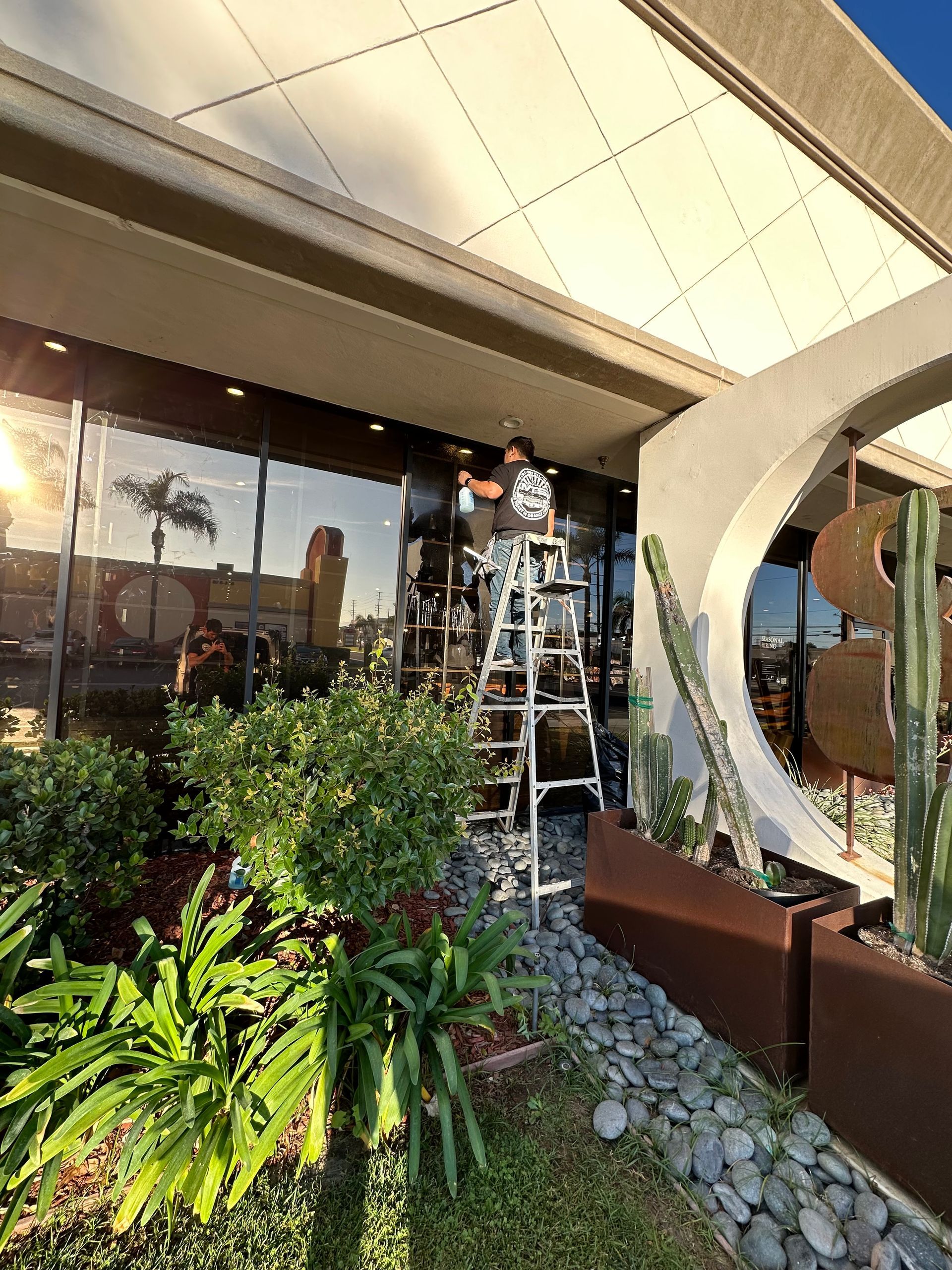 A man is standing on a ladder outside of a building.
