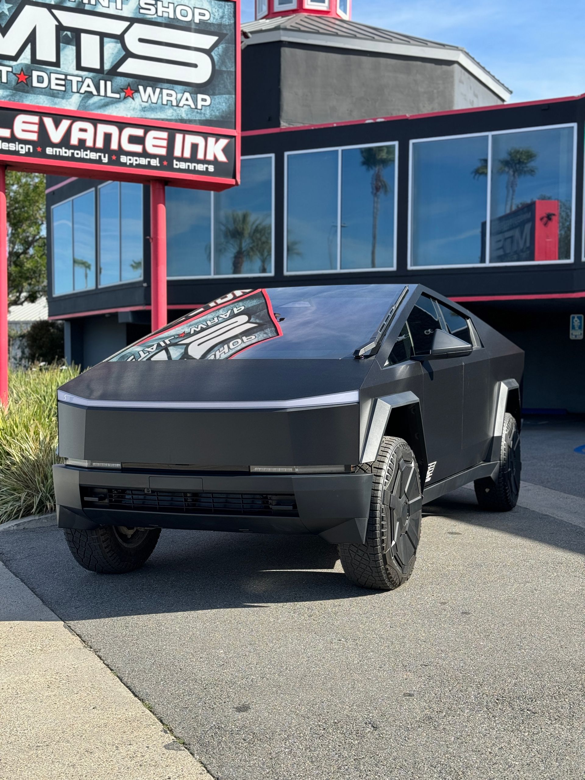 A black car is parked in front of a building.