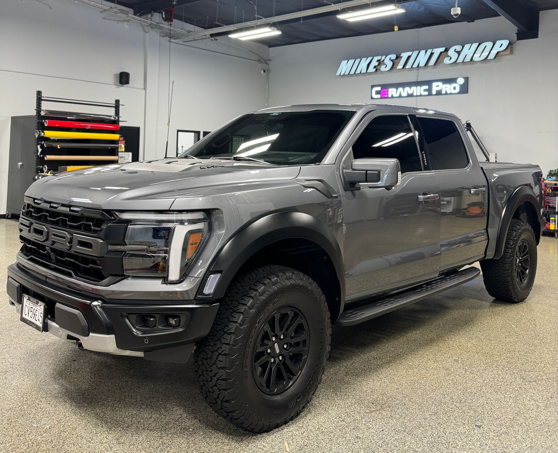 Gray lifted Ford pickup in an auto shop with tinting equipment