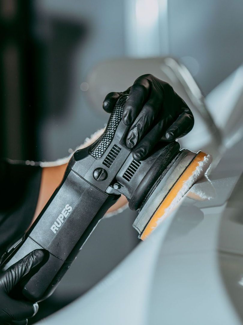 A man is polishing a black car with a machine