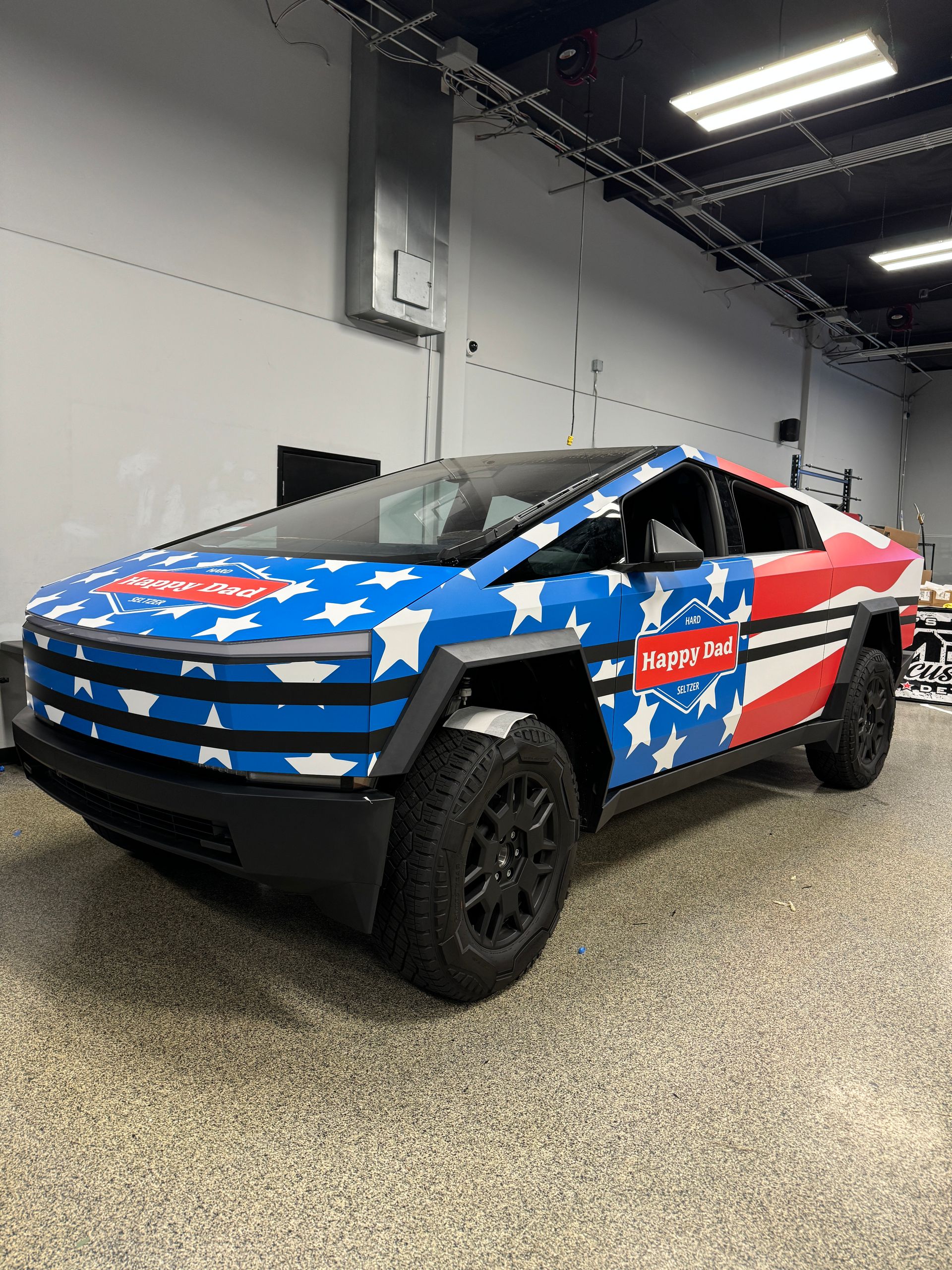 A black Ford Raptor truck parked in a well-lit workshop with a Ceramic Pro sign on the wall.