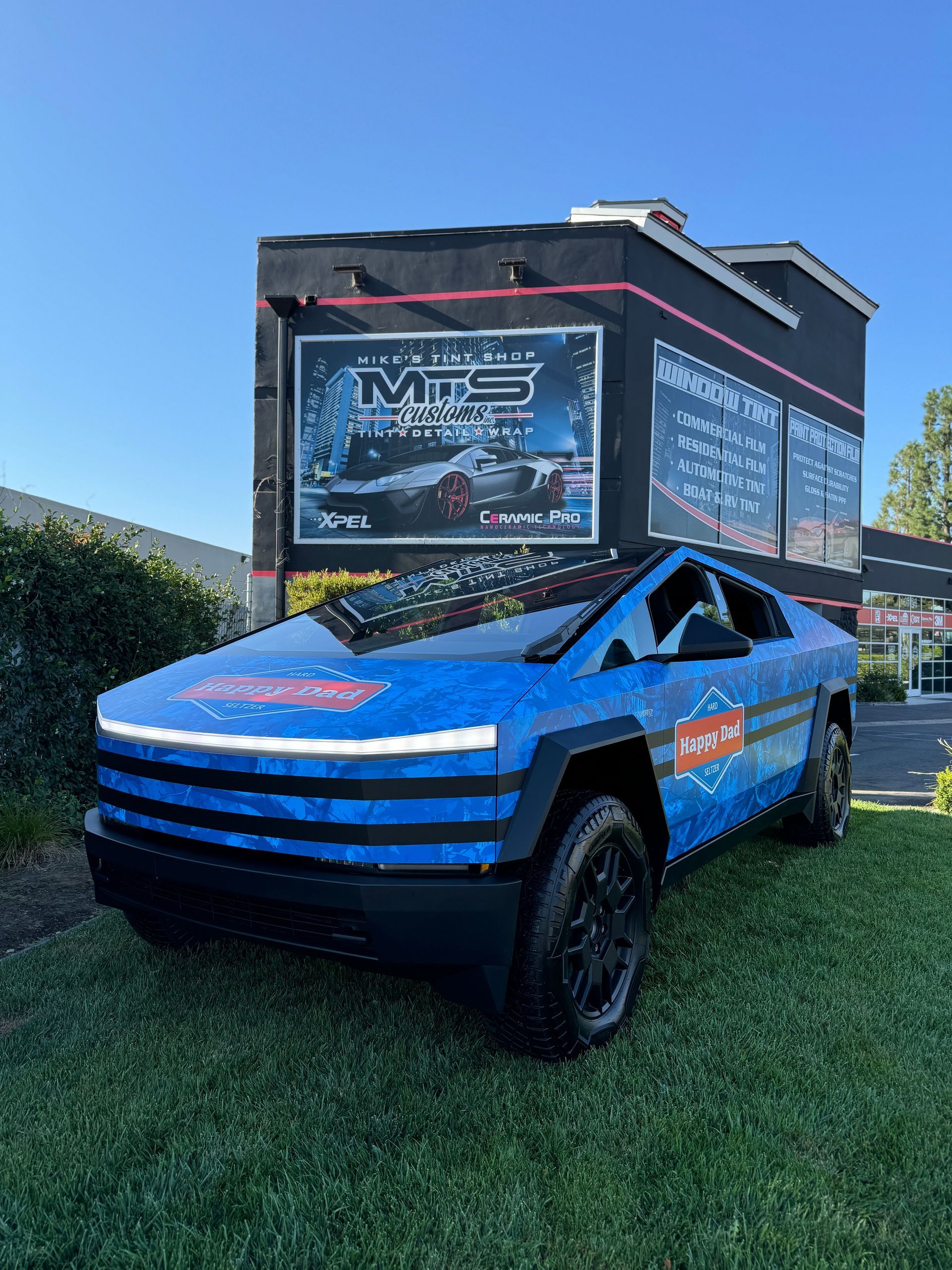 Blue sports car parked outside MTS with a red sign in a sunny lot