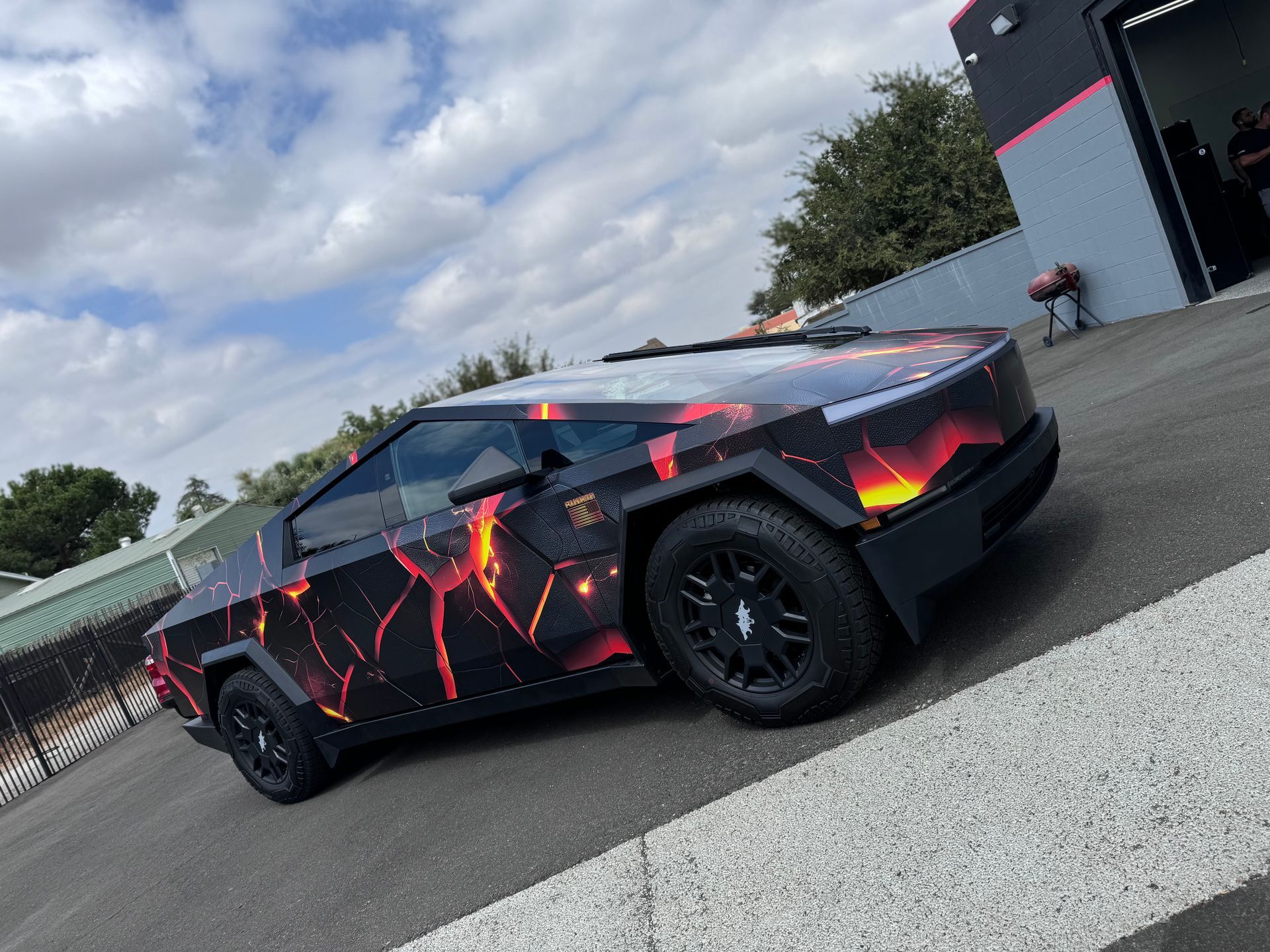 A tesla model s with an american flag wrap is parked in a garage.