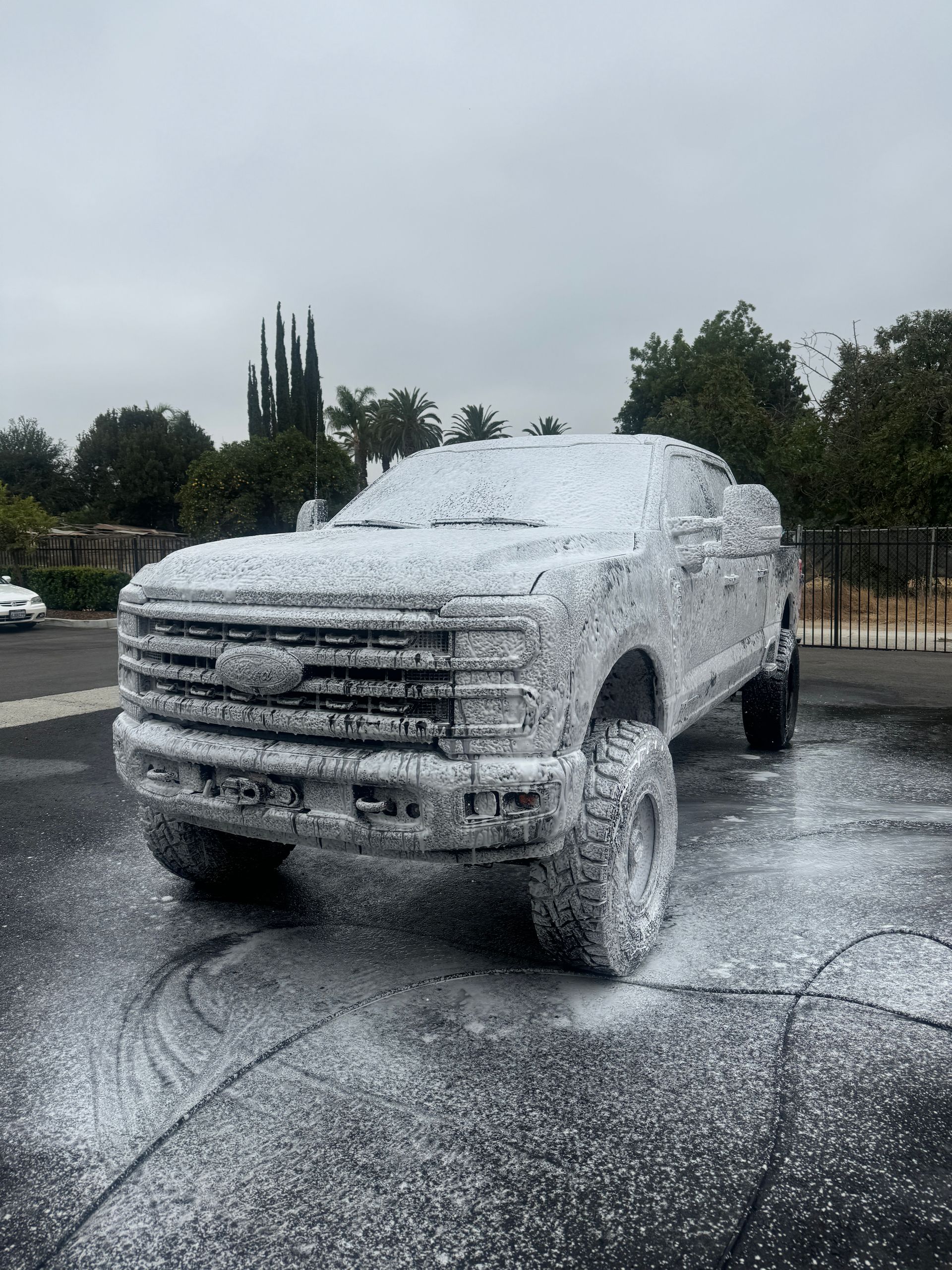 A truck is covered in foam in a parking lot.