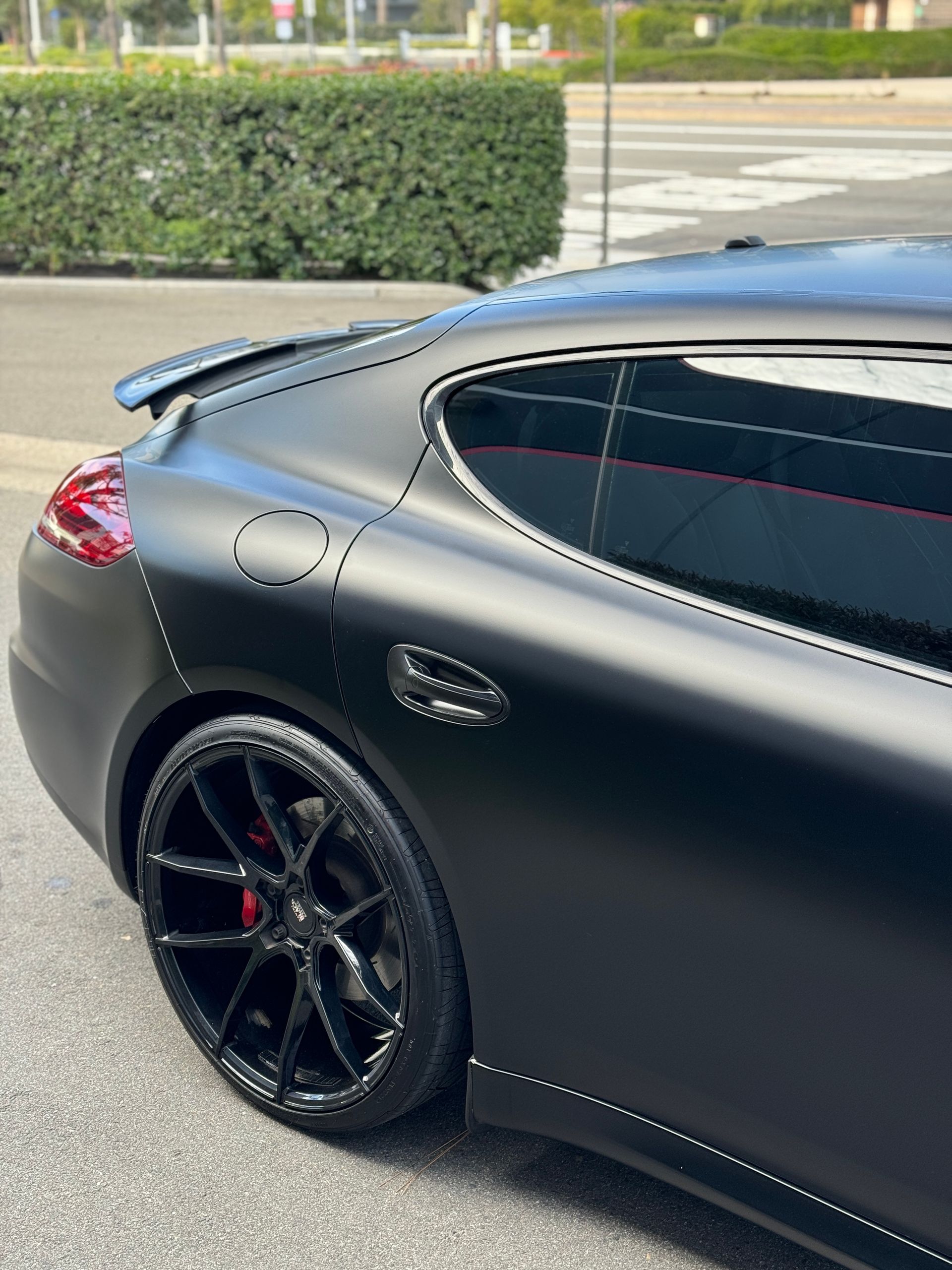 A black porsche panamera is parked on the side of the road.