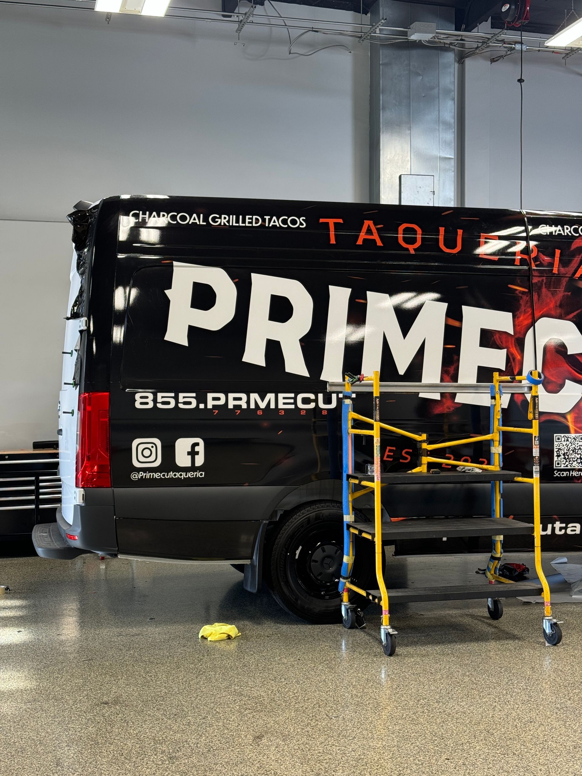 A black van with the word primec on it is parked in a garage.