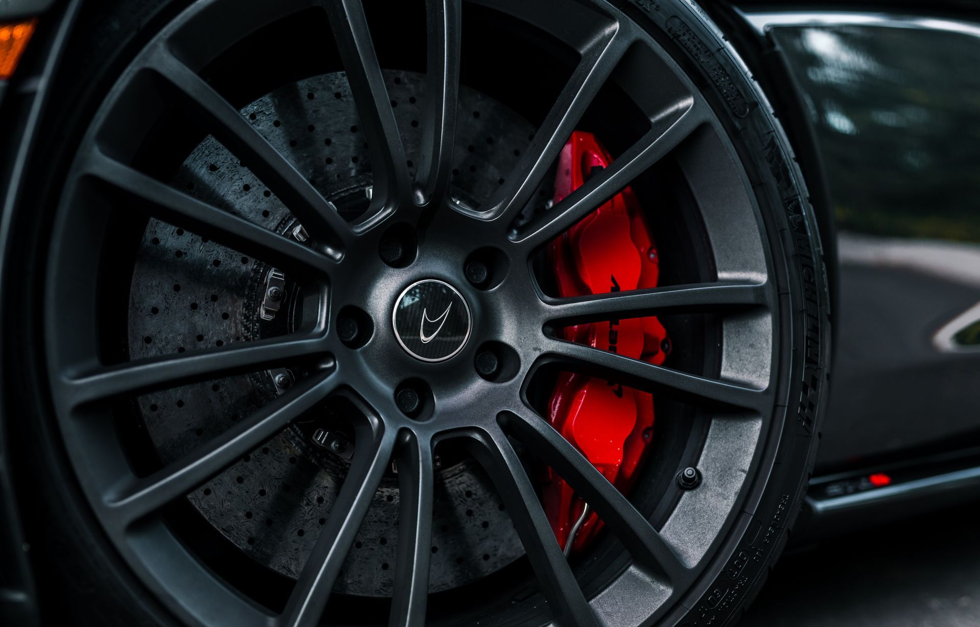 A close up of a car wheel with a red brake caliper