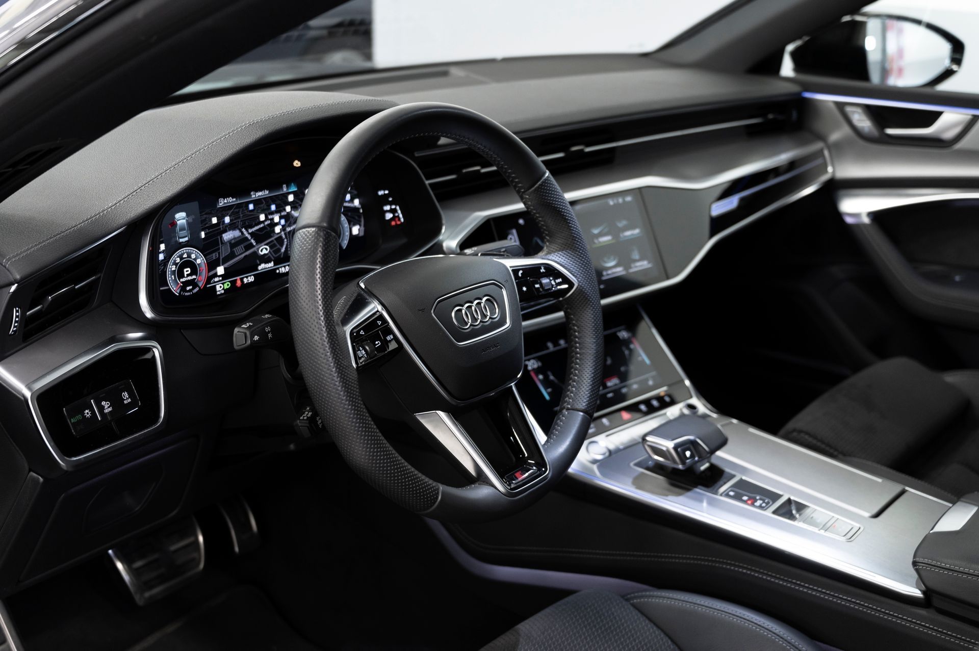 A person wearing black gloves is cleaning the dashboard of a car.