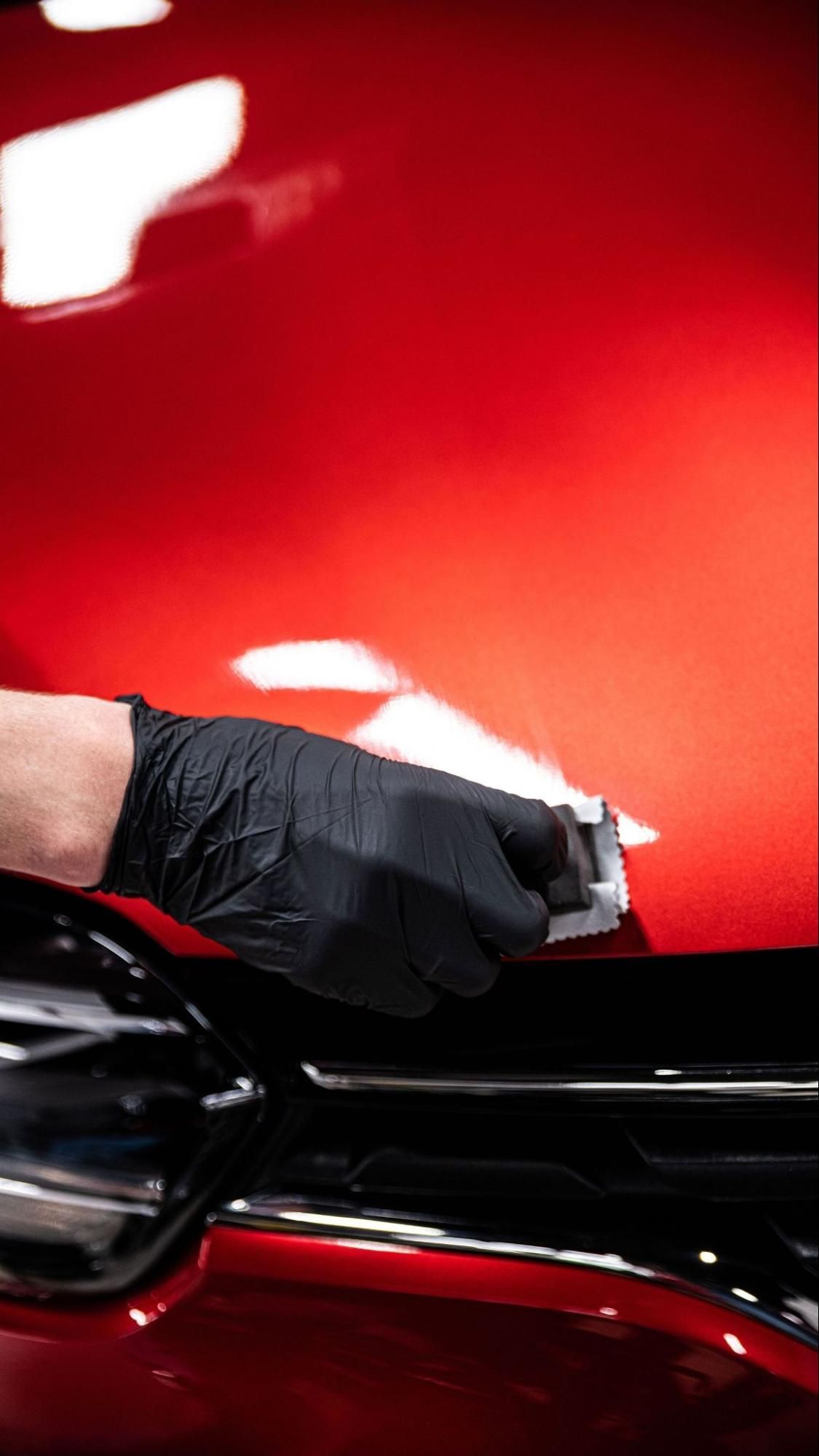 Person using a tool to work on a car window.