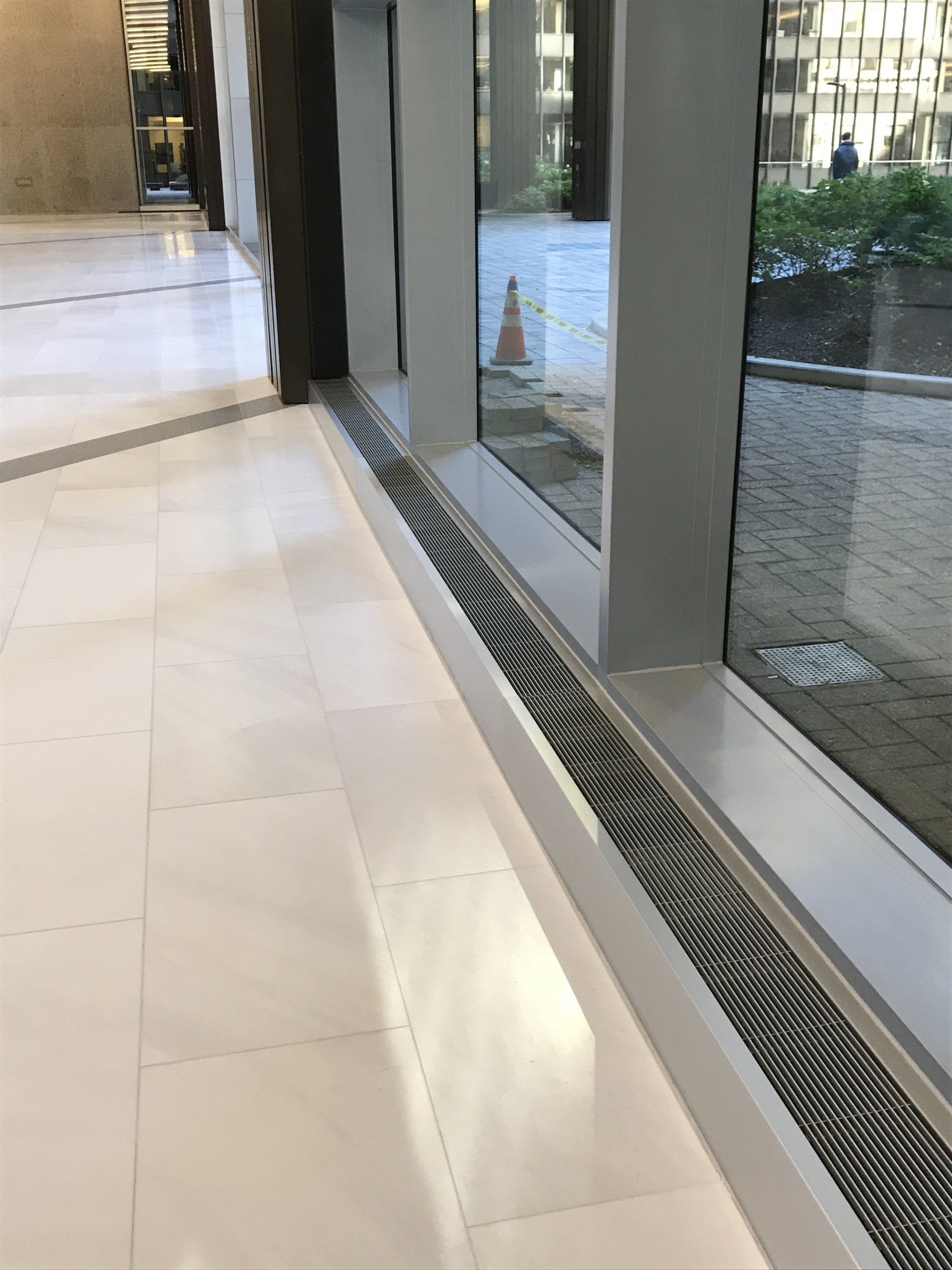 A hallway with a window and a drain on the floor