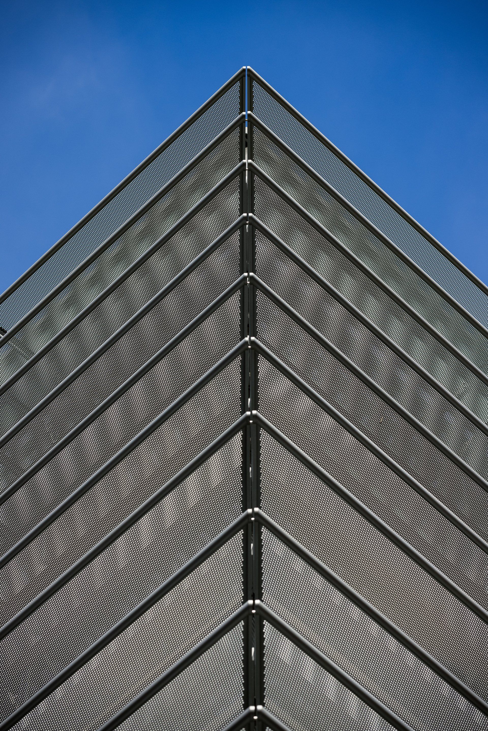 Looking up at the corner of a building with a blue sky in the background.