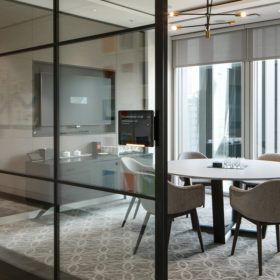 A conference room with a glass wall and a table and chairs.