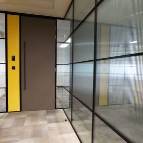 A hallway with glass walls and a yellow door
