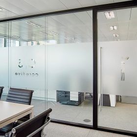 A conference room with a table and chairs and a glass wall.