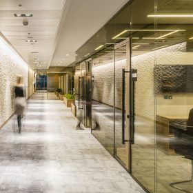 A long hallway with glass doors and people walking down it.
