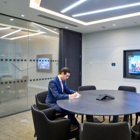 A man in a suit is sitting at a round table in a conference room.