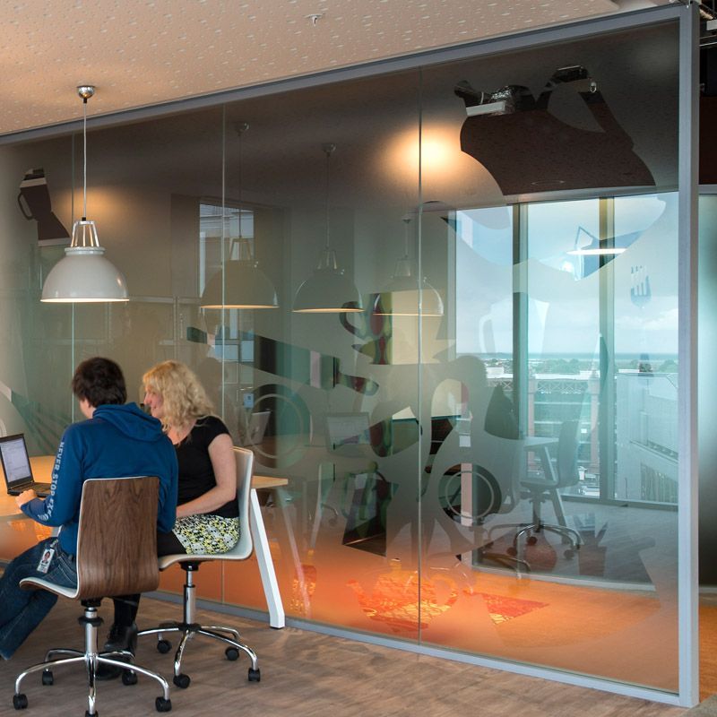 Two people are sitting at a desk in front of a glass wall