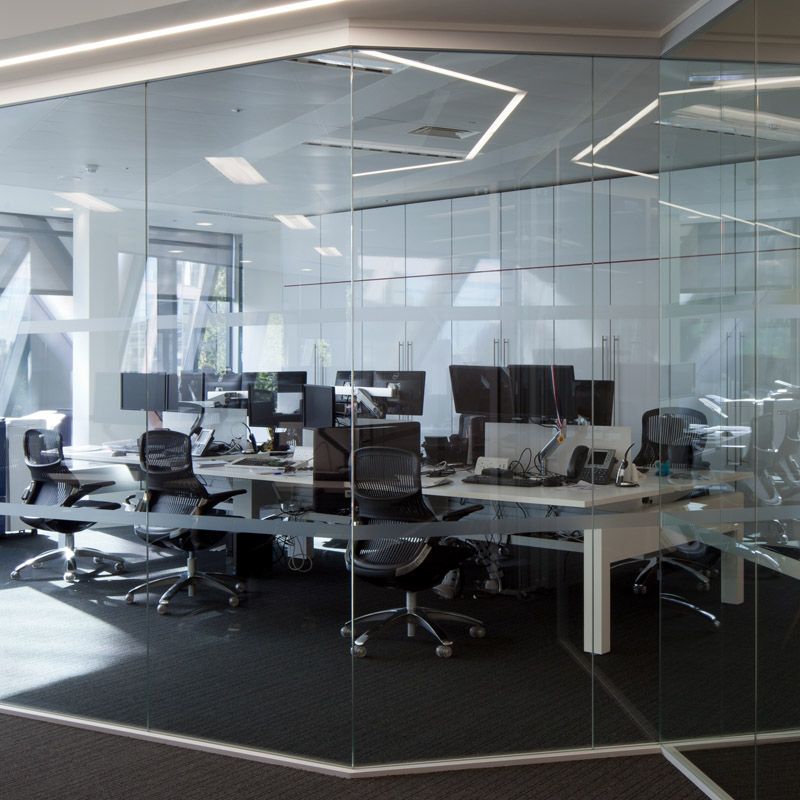 An office with a glass wall and a lot of desks and chairs
