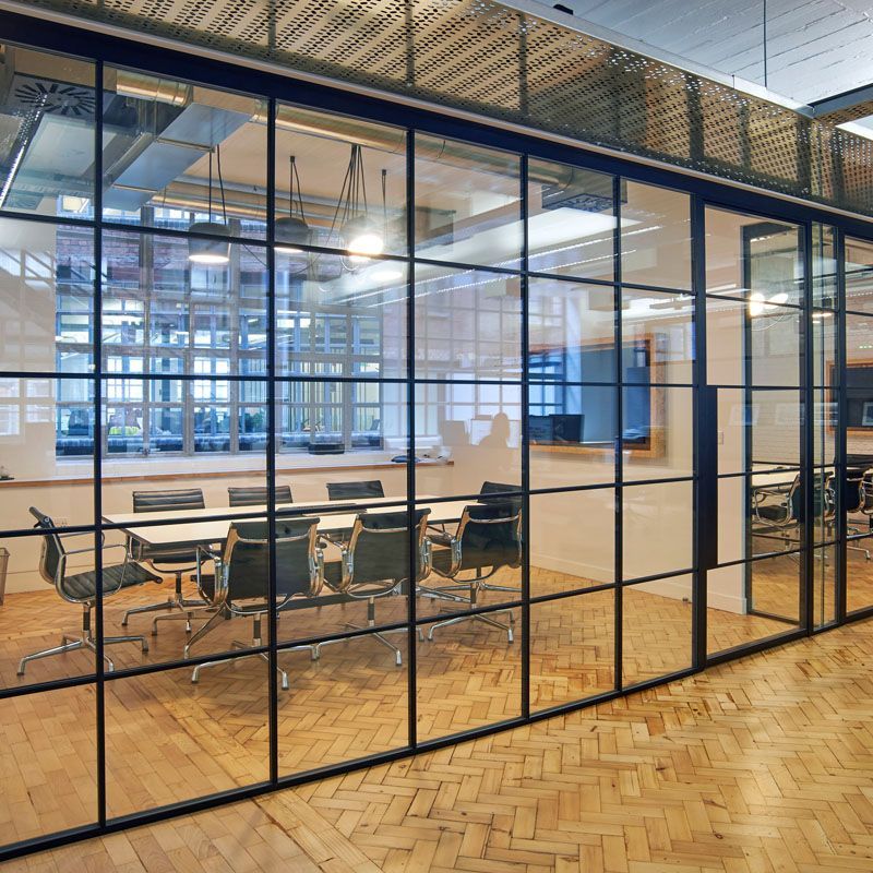 A conference room with tables and chairs behind a glass wall.