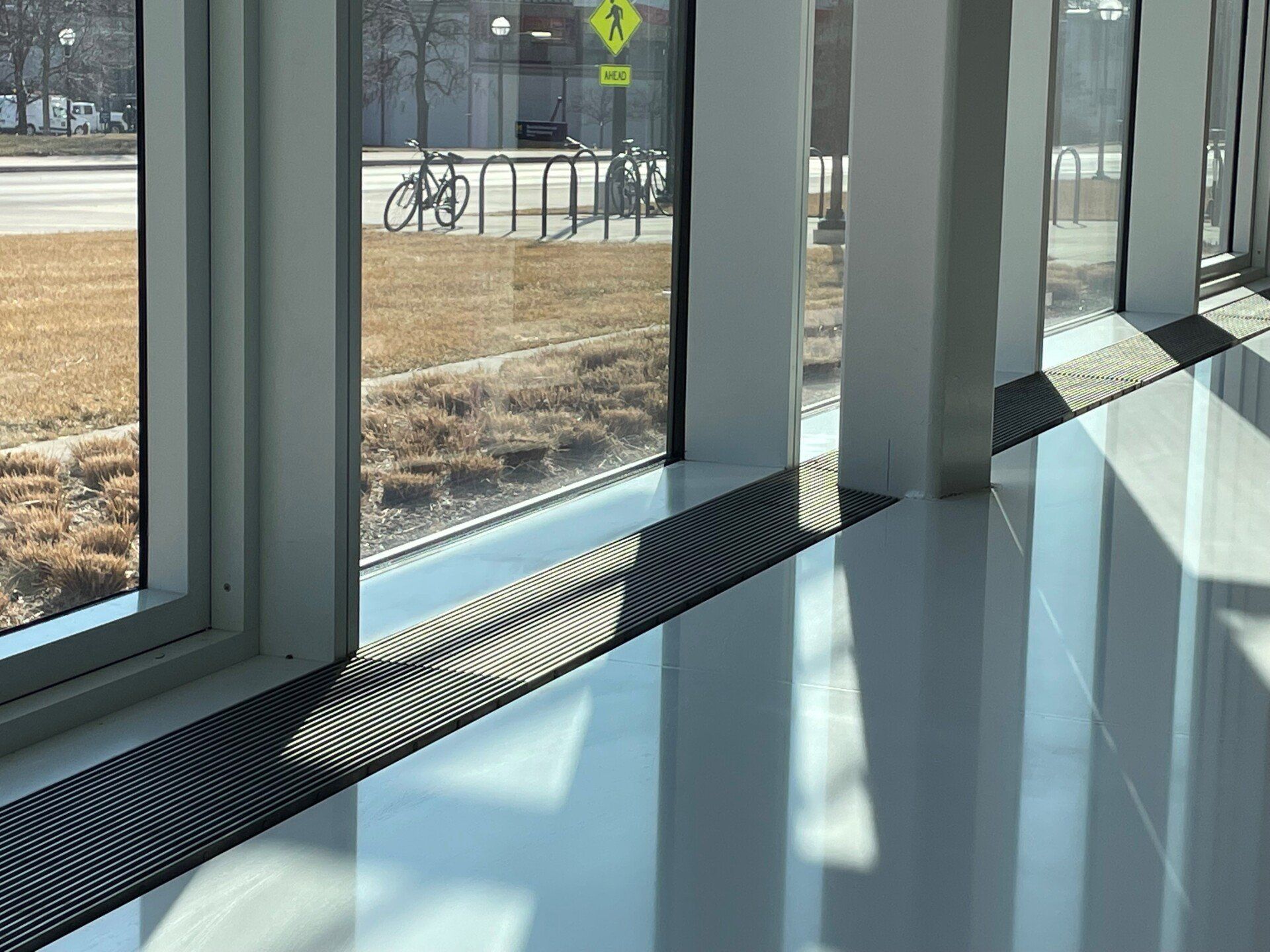 A hallway with a lot of windows and a bicycle rack in the background