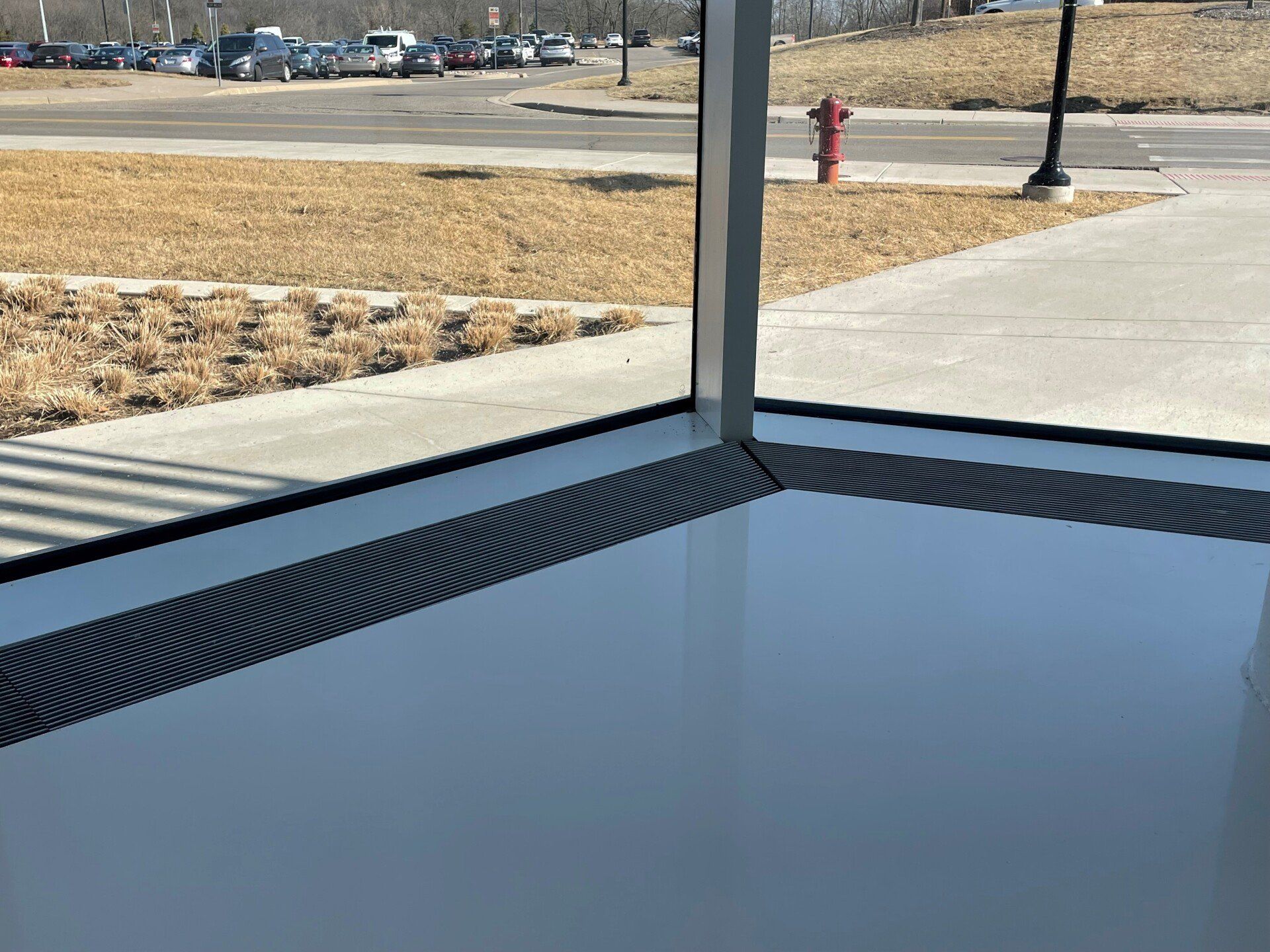 A window with a view of a parking lot and a fire hydrant.