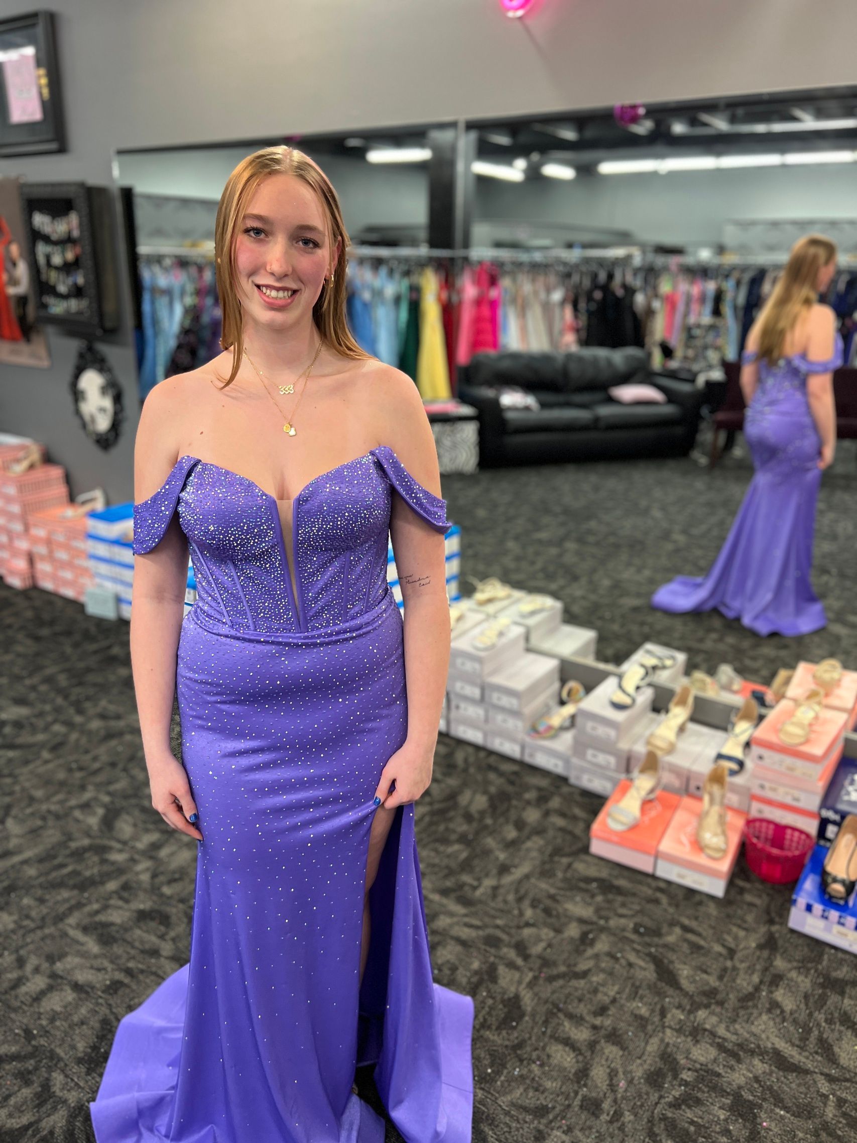 Woman in a lavender off-the-shoulder gown with slit, in a dress shop.