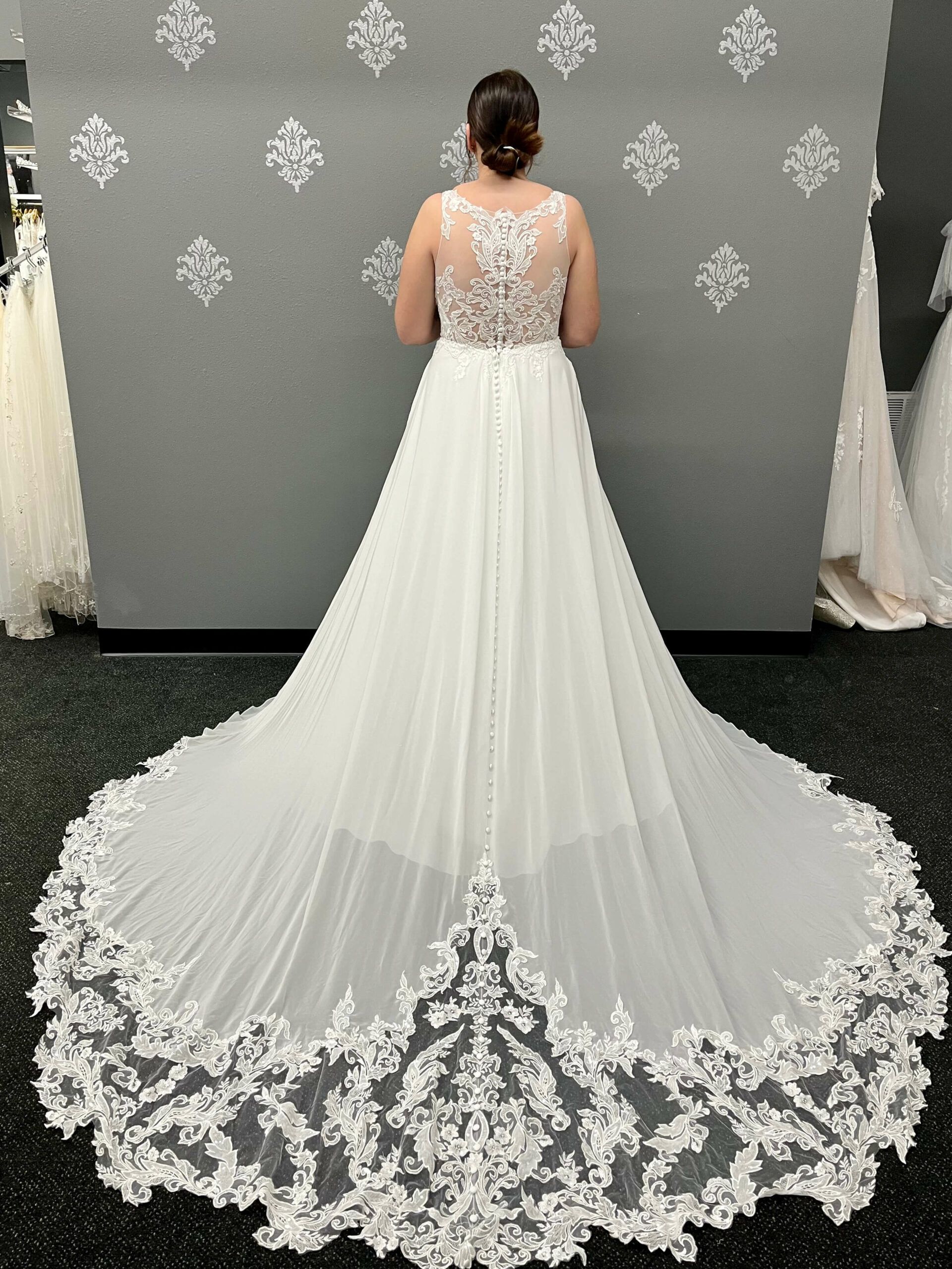 Woman in a white wedding dress with lace detail on the bodice and a long train.