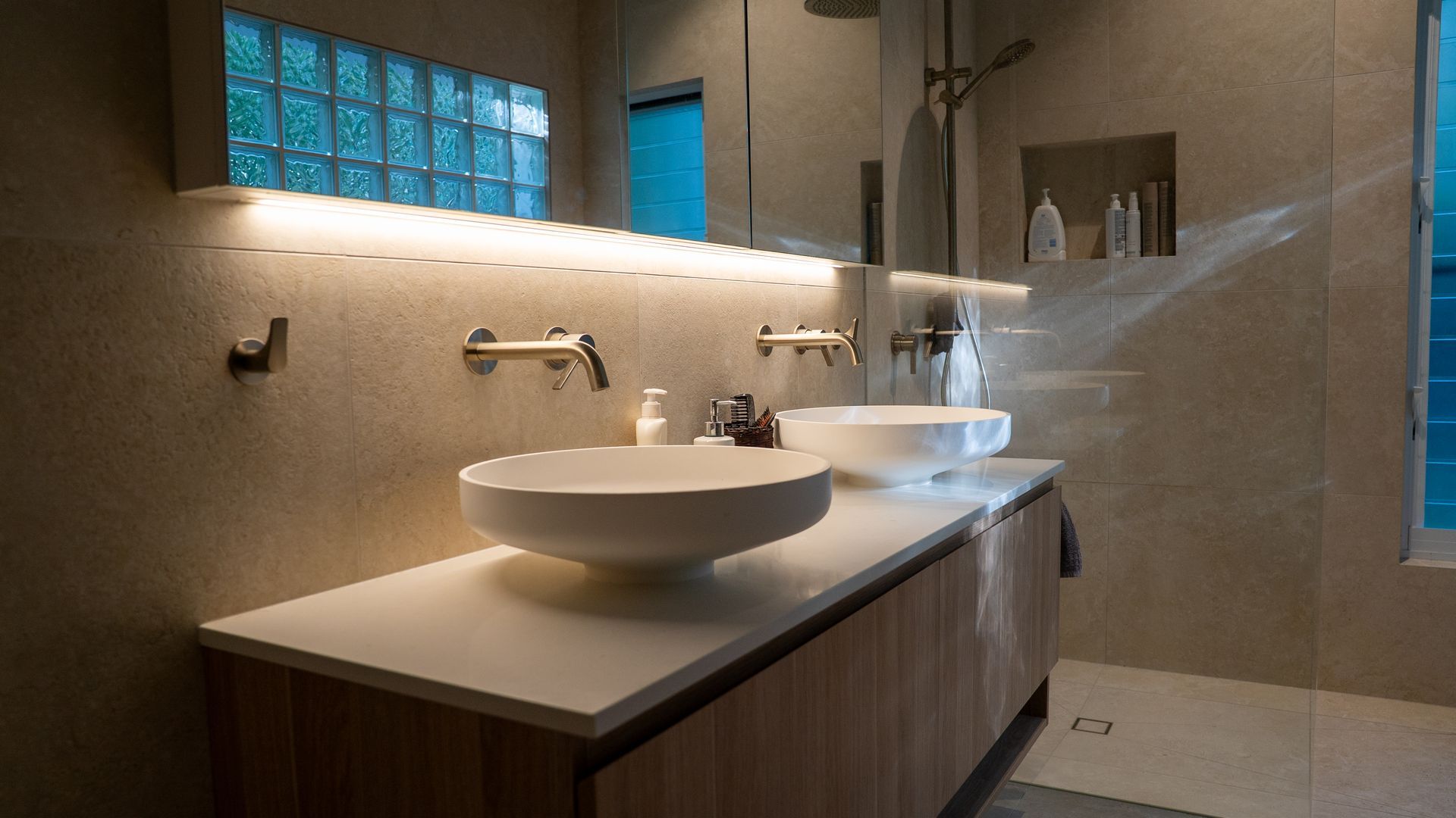 Modern Bathroom with Double Vessel Sinks, Wood Vanity, Wall Mirror, and Blue Accent Window — Ralph Ottmann Electrical in Pomona, QLD