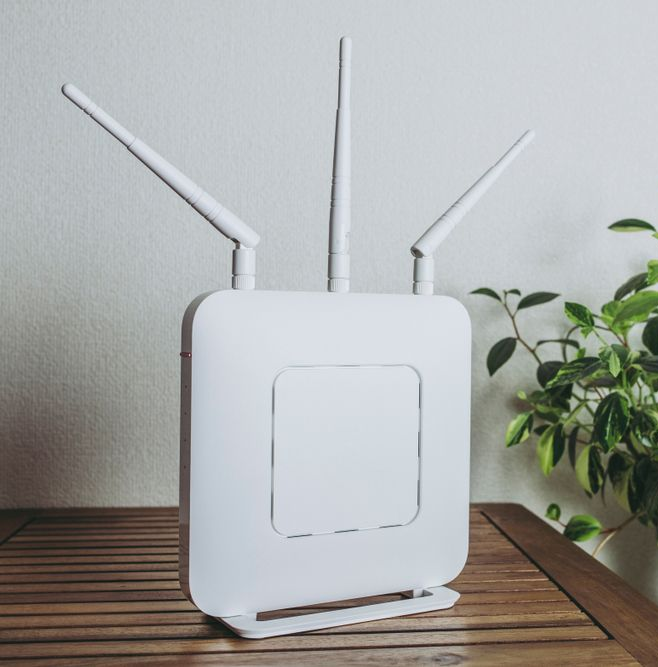 White Wi-fi Router With Three Antennas on Wooden Surface — Ralph Ottmann Electrical in Pomona, QLD