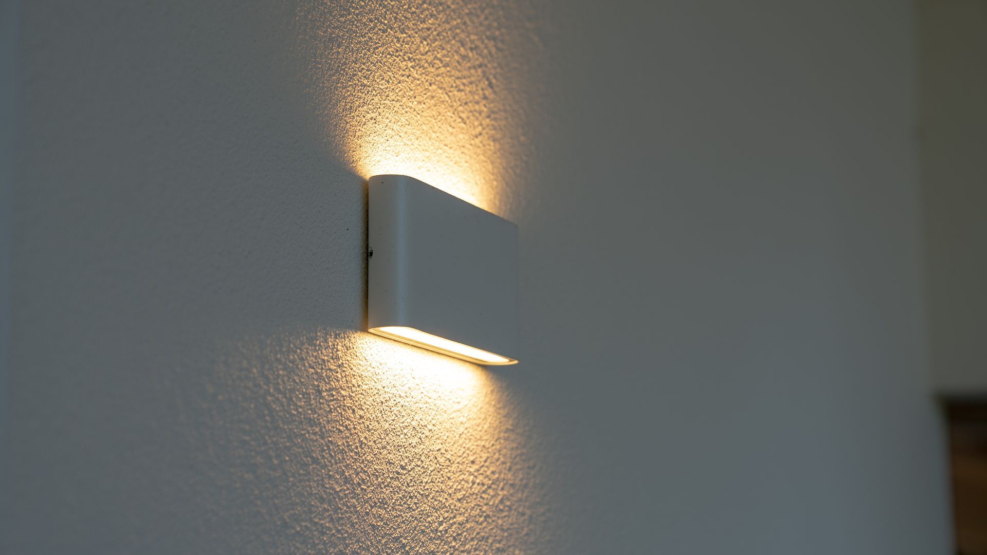 Wall-Mounted Modern Light Fixture Casting Warm Light on A Textured White Wall — Ralph Ottmann Electrical in Pomona, QLD