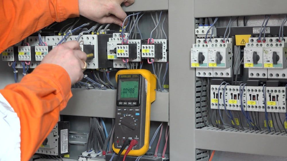Electrician Using a Multimeter in a Control Panel — Ralph Ottmann Electrical in Pomona, QLD