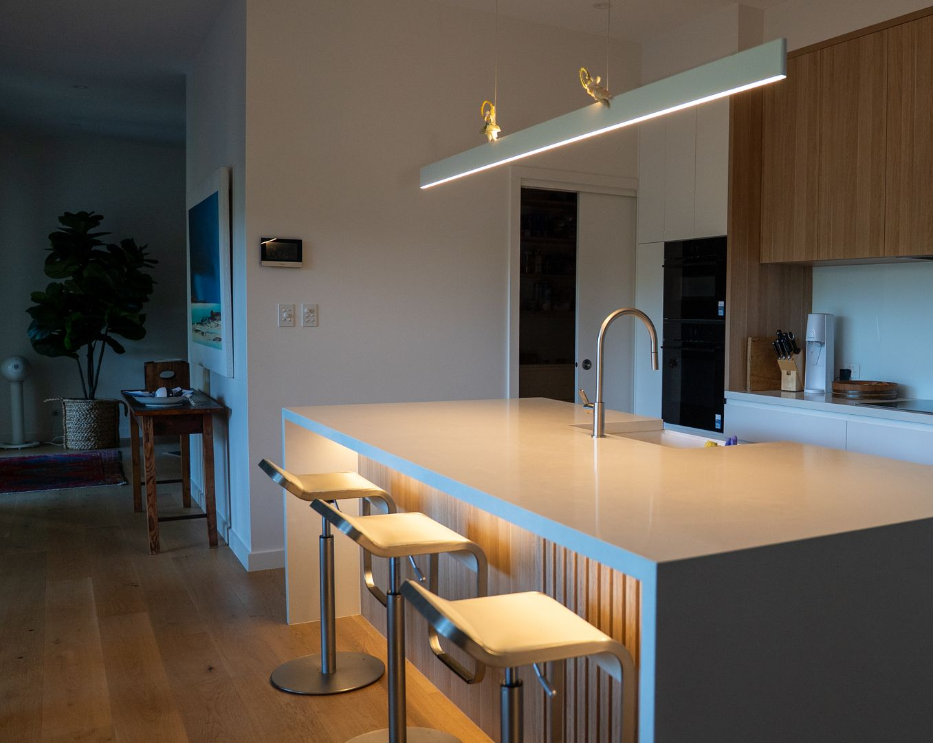 Modern Kitchen Island with Bar Stools, Pendant Light, and Open Dining Area Beyond — Ralph Ottmann Electrical in Pomona, QLD