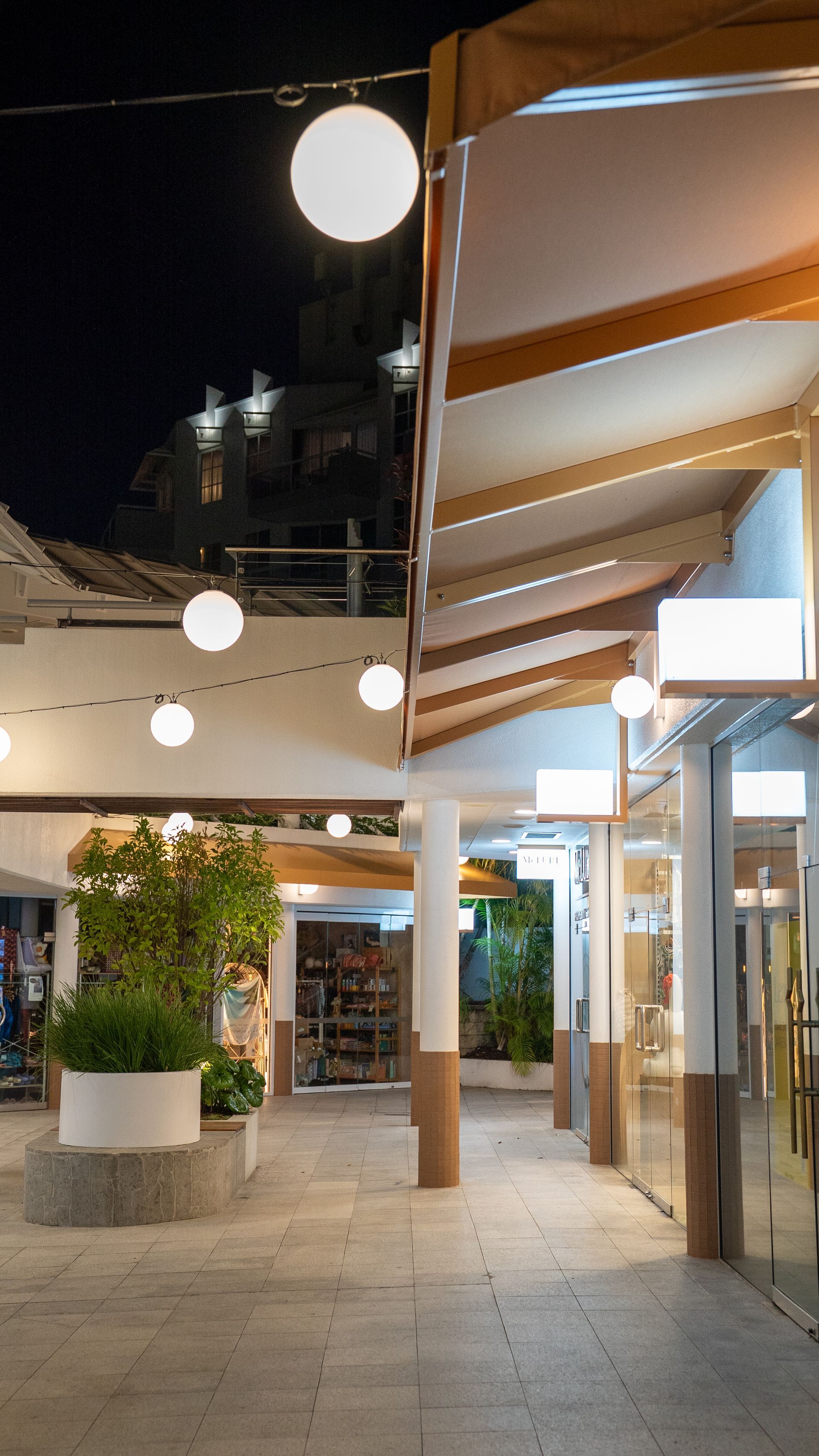 Outdoor Shopping Walkway at Night with Round Hanging Lights — Ralph Ottmann Electrical in Pomona, QLD