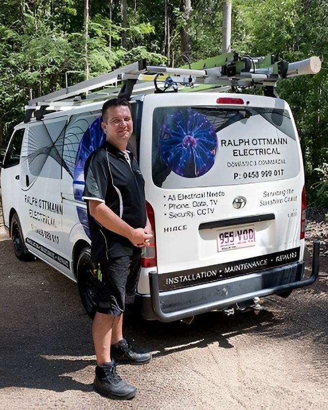 Man Stands Next to a White Van With Ralph Ottmann Electrical Signage — Ralph Ottmann Electrical in Pomona, QLD