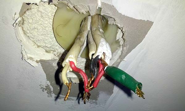 Exposed Electrical Wires Protruding From a Damaged Ceiling Hole — Ralph Ottmann Electrical in Pomona, QLD