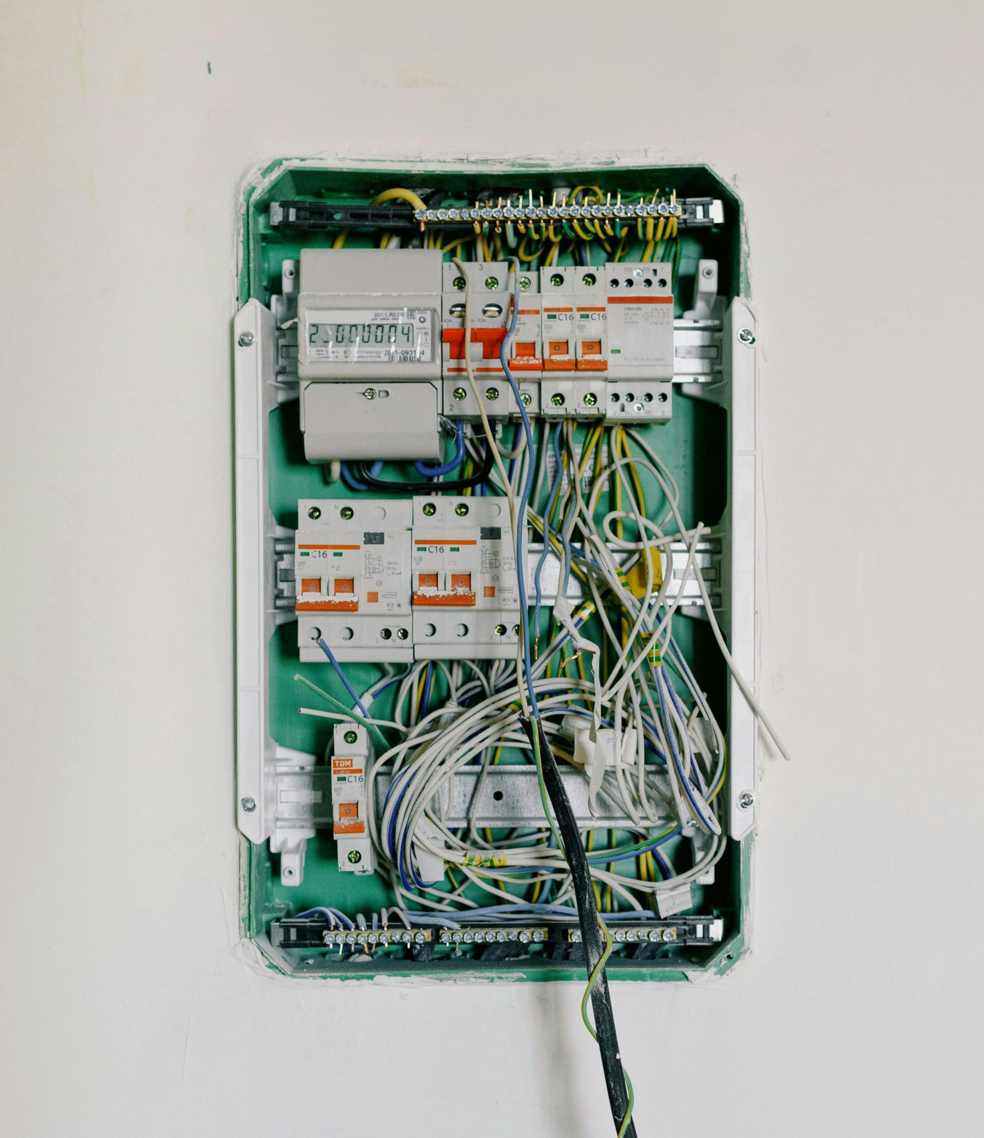 Open electrical panel with circuit breakers and exposed wiring on a wall  — Ralph Ottmann Electrical in Pomona, QLD