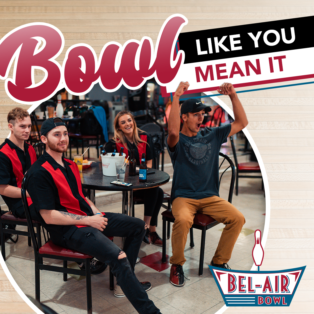 A group of people are sitting at tables in a bowling alley with a sign that says bowl like you mean it